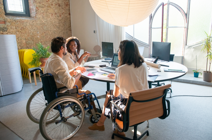 Trois personnes travaillent ensemble dans un bureau, échangeant des idées et collaborant activement. L’une d’elles en fauteuil roulant, illustrant un environnement inclusif et dynamique. Trois personnes travaillent ensemble dans un bureau, échangeant des idées et collaborant activement. L’une d’elles en fauteuil roulant, illustrant un environnement inclusif et dynamique.